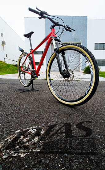 Bicicleta vermelha com pneu com faixa bege estacionada em frente ao prédio