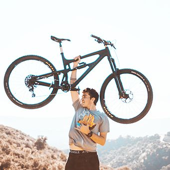 Homem segurando uma bicicleta no alto somente com uma mão